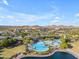 Aerial view of a resort-style pool, club house, palm trees with mountain views at 10931 S Santa Columbia Dr, Goodyear, AZ 85338
