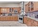 Well-appointed kitchen featuring wooden cabinets, travertine floors, and modern stainless steel appliances at 10931 S Santa Columbia Dr, Goodyear, AZ 85338