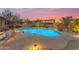 Relaxing pool area featuring stone patio, mature desert landscaping, and evening lighting at 10931 S Santa Columbia Dr, Goodyear, AZ 85338