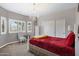 Inviting bedroom with neutral walls, chandelier, shutters, and a cozy bed with a red blanket at 1589 E Manor Dr, Casa Grande, AZ 85122