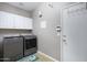 Functional laundry room with washer, dryer, white cabinets, and a door leading to the outside at 1589 E Manor Dr, Casa Grande, AZ 85122