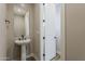 Modern half bath features a pedestal sink, updated fixtures, and a door leading to another space at 2121 W Sonoran Desert Dr # 45, Phoenix, AZ 85085