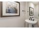 Stylish powder room featuring a pedestal sink, dark hardware, and modern artwork at 2121 W Sonoran Desert Dr # 45, Phoenix, AZ 85085