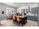 Open concept kitchen with stainless steel appliances, center island, gray cabinets, and adjacent dining area at 2415 W Hazelhurst Ct, Anthem, AZ 85086