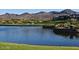Community pond with grassy shoreline in a mountain setting with luxury homes in the background at 2415 W Hazelhurst Ct, Anthem, AZ 85086