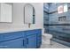 Bathroom featuring blue cabinets, dual sinks, shower with blue tile, and modern fixtures at 30634 W Latham St, Buckeye, AZ 85326
