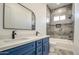Bathroom featuring blue cabinets, dual sinks, and tiled shower and bathtub at 30634 W Latham St, Buckeye, AZ 85326
