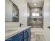 Bathroom featuring blue cabinets, dual sinks, and tiled shower and bathtub at 30634 W Latham St, Buckeye, AZ 85326