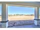 A covered patio offers views of a bright blue sky, a dirt lot, and a neighboring community at 30634 W Latham St, Buckeye, AZ 85326
