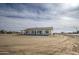 A clear shot of a one-story white home with a large front yard covered in sand, complemented by a blue sky at 30634 W Latham St, Buckeye, AZ 85326