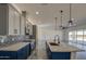 A modern kitchen with gray cabinets, white countertops, and stainless steel appliances seamlessly integrates into the living space at 30634 W Latham St, Buckeye, AZ 85326