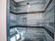 Stylish shower featuring blue tile, black accents, a bench, and geometric floor tiles at 30634 W Latham St, Buckeye, AZ 85326