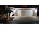 Night view of a well-lit two car garage featuring a spacious driveway at 10549 E Cedar Waxwing Dr, Sun Lakes, AZ 85248