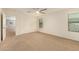 Spacious bedroom featuring neutral carpeting, ceiling fan, and ample natural light from windows at 11128 E Segura Ave, Mesa, AZ 85212