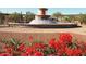 The fountain in the community is surrounded by red flowers and green plants and offers a welcoming atmosphere at 11128 E Segura Ave, Mesa, AZ 85212