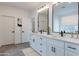 Beautiful primary bath with double vanity sinks, white cabinetry, a large mirror and modern fixtures at 11206 E Crescent Ave, Mesa, AZ 85208