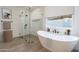 Bright bathroom featuring a soaking tub, glass enclosed shower, and neutral color palette at 11206 E Crescent Ave, Mesa, AZ 85208