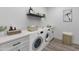 Bright laundry room featuring a Bosch washer and dryer, white cabinets, quartz counters, and wood-look tile floors at 11206 E Crescent Ave, Mesa, AZ 85208