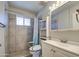 Well-lit bathroom features a toilet with safety handles, complemented by a tiled shower and vanity at 11407 N 111Th Ave, Sun City, AZ 85351