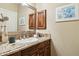 Bathroom vanity with granite countertop, wood cabinets, decorative mirror, and an oval-shaped sink at 12610 E Cortez Dr, Scottsdale, AZ 85259