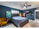 Modern bedroom featuring a dark blue accent wall, ceiling fan, and ample natural light at 13845 N 41St Ave, Phoenix, AZ 85053