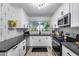 Modern kitchen featuring white cabinets, black countertops, stainless steel appliances, and geometric backsplash at 13845 N 41St Ave, Phoenix, AZ 85053