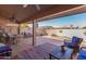 Relaxing covered patio area with comfortable seating, colorful decor, and a view of the landscaped backyard at 14718 W Ravenswood Dr, Sun City West, AZ 85375