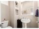 A traditional powder room with stylish wall shelves, pedestal sink, and neutral decor at 16600 N Thompson Peak Pkwy # 1052, Scottsdale, AZ 85260