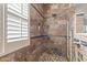 Shower with stone tile, shower niche, and pebble floor at 17634 W Verdin Rd, Goodyear, AZ 85338