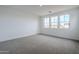 Spacious bedroom with neutral carpet, white walls, and three windows, providing ample natural light at 21250 E Sparrow Dr, Queen Creek, AZ 85142