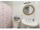 Bathroom with a pedestal sink, a round ornate mirror and a shower with a red and white curtain at 2812 W Heatherbrae Dr, Phoenix, AZ 85017