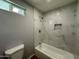 Bathroom with gray walls, a bathtub, and marble look shower tiles at 318 E Hill Dr, Avondale, AZ 85323