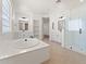 Bright bathroom featuring a soaking tub, dual vanities, and a glass-enclosed shower for a spa-like experience at 3557 S Halsted Ct, Chandler, AZ 85286