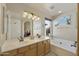 Bright bathroom featuring double sink vanity, bathtub, art, and big mirror at 4439 E Coyote Wash Dr, Cave Creek, AZ 85331