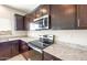 Close up of a modern kitchen featuring granite countertops and stainless steel appliances and dark wood cabinetry at 5055 S 251St Dr, Buckeye, AZ 85326