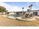 A lovely backyard featuring a kidney-shaped pool, lounge chairs, palm trees, and white exterior at 718 W Vine Ave, Mesa, AZ 85210