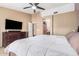 Comfortable bedroom featuring a ceiling fan, dresser with TV, and access to the ensuite bathroom at 7214 W Crest Ln, Glendale, AZ 85310