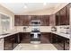 Well-equipped kitchen featuring granite countertops, stainless steel appliances, and dark wood cabinetry at 7214 W Crest Ln, Glendale, AZ 85310