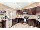 Well-equipped kitchen with stainless steel appliances, granite countertops, and dark wood cabinetry at 7214 W Crest Ln, Glendale, AZ 85310