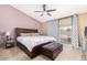 Main bedroom featuring a ceiling fan, sliding glass door, storage bed frame, and neutral walls at 7214 W Crest Ln, Glendale, AZ 85310