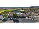 Aerial view featuring a community clubhouse, pool, tennis courts, and parking within lush landscaping at 8199 E Sweet Acacia Dr, Gold Canyon, AZ 85118