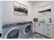 Well-equipped laundry room with a front-load washer/dryer, white cabinetry, and decorative tile flooring at 9398 E Cloudview Ave, Gold Canyon, AZ 85118