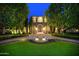 Front exterior featuring a stone facade, fountain, manicured landscaping, and illuminated trees at 9547 N 55Th St, Paradise Valley, AZ 85253