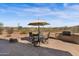 Relaxing back patio area featuring outdoor kitchen, fire pit, and dining set under a camouflage umbrella at 13121 S 178Th Ave, Goodyear, AZ 85338