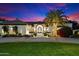 Stunning home exterior at dusk with a well-manicured lawn, inviting entrance and a lovely illuminated palm tree at 13670 N 85Th Pl, Scottsdale, AZ 85260