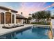 Luxury pool featuring a manicured lawn, lounge chairs, and mature trees against a sunset backdrop at 13670 N 85Th Pl, Scottsdale, AZ 85260