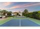 Well-maintained tennis court with lush greenery, set against a beautiful home and evening sky at 13670 N 85Th Pl, Scottsdale, AZ 85260