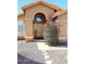 Charming home's front entrance has an arched doorway and a desert landscaped yard with rock cover at 14460 N 100Th Way, Scottsdale, AZ 85260