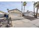 Attached two-car garage with desert landscaping featuring palm trees and a concrete driveway at 1780 E Countrywalk Ln, Chandler, AZ 85225