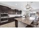 Kitchen with center island, stainless appliances, dark cabinets and pendant lighting at 22854 E Sonoqui Blvd, Queen Creek, AZ 85142